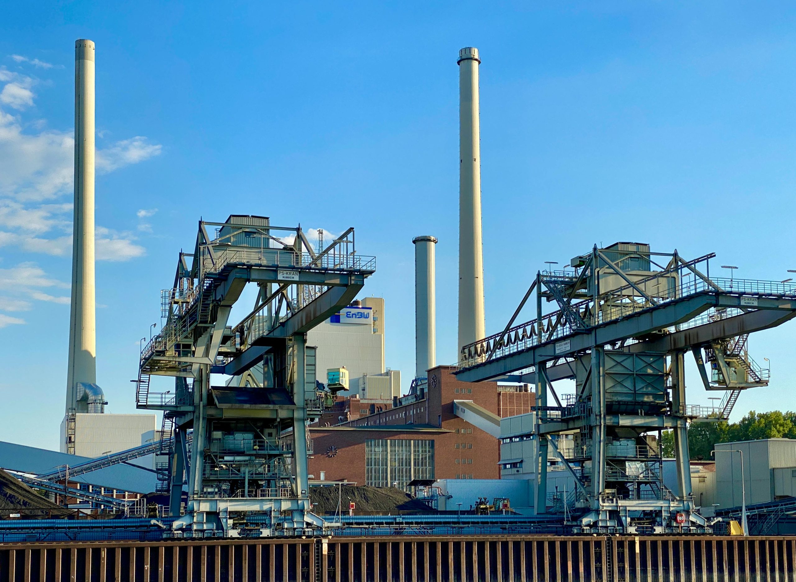 Industrial facility in Karlsruhe, Germany, featuring tall chimneys and blue sky.
